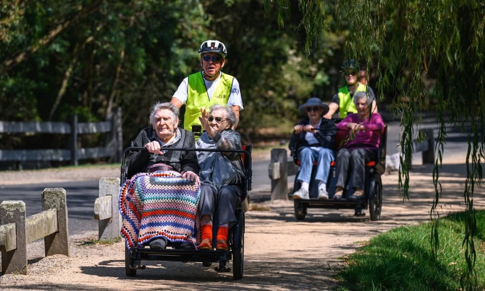 An older passenger being carried in a Ricky Rickshaw
